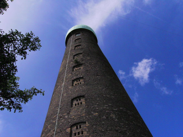 a tappering brick tower with a green copper onion roof